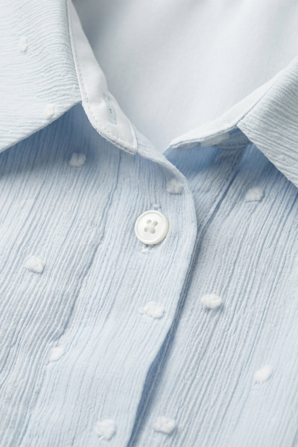 Blusa azzurra ricamata a pois con bottoni