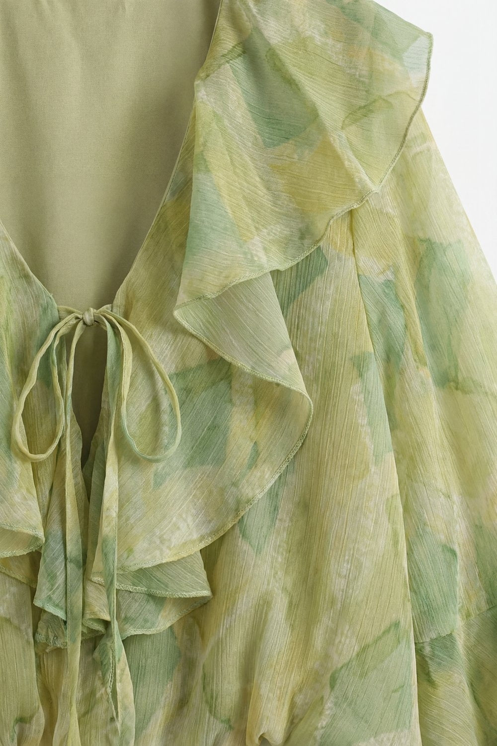 Blusa trasparente verde chiaro con volant e nodo frontale