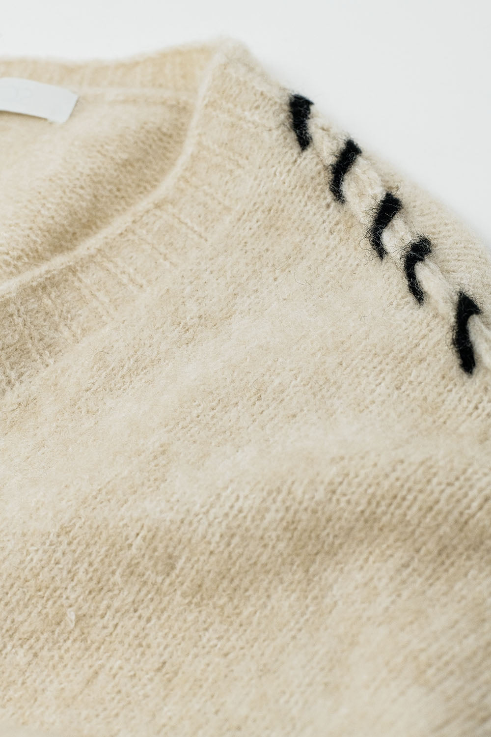 Cardigan aperto color crema con finiture nere in maglia grossa