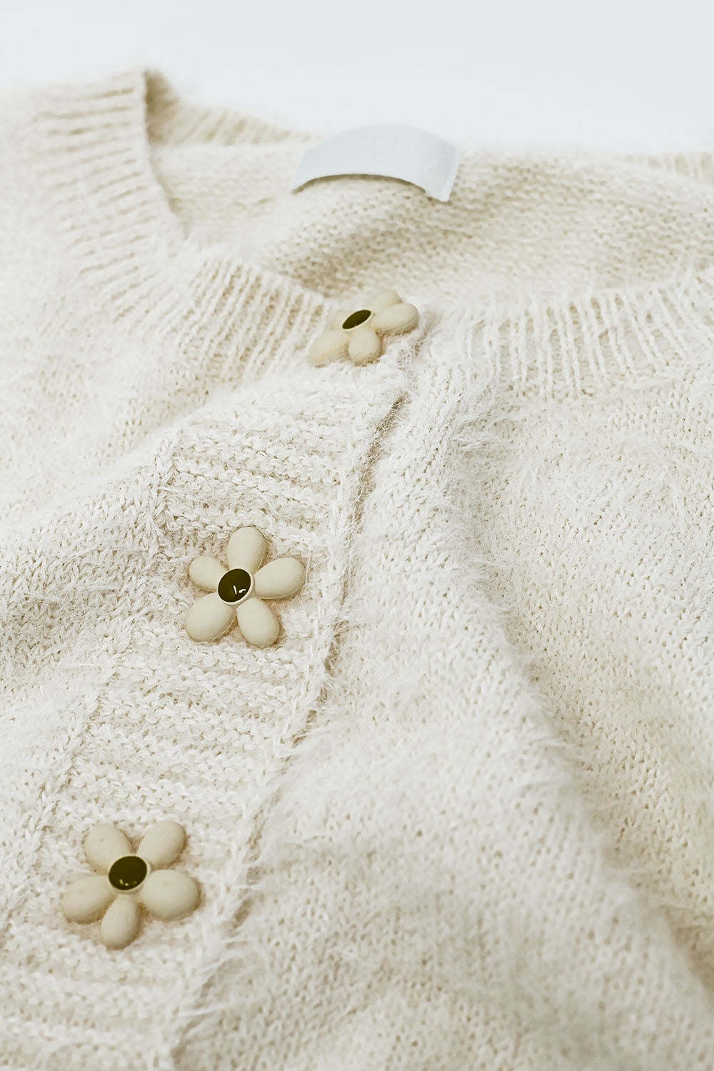 Cardigan corto e soffice color panna con bottoni a fiore