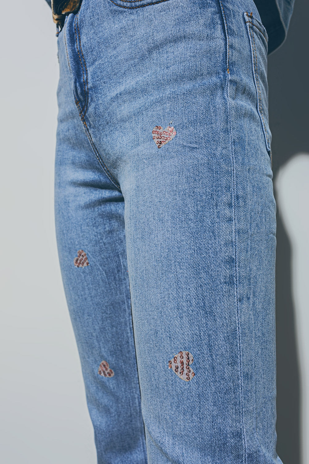 Jeans con cuore impreziosito e orlo strappato in lavaggio medio