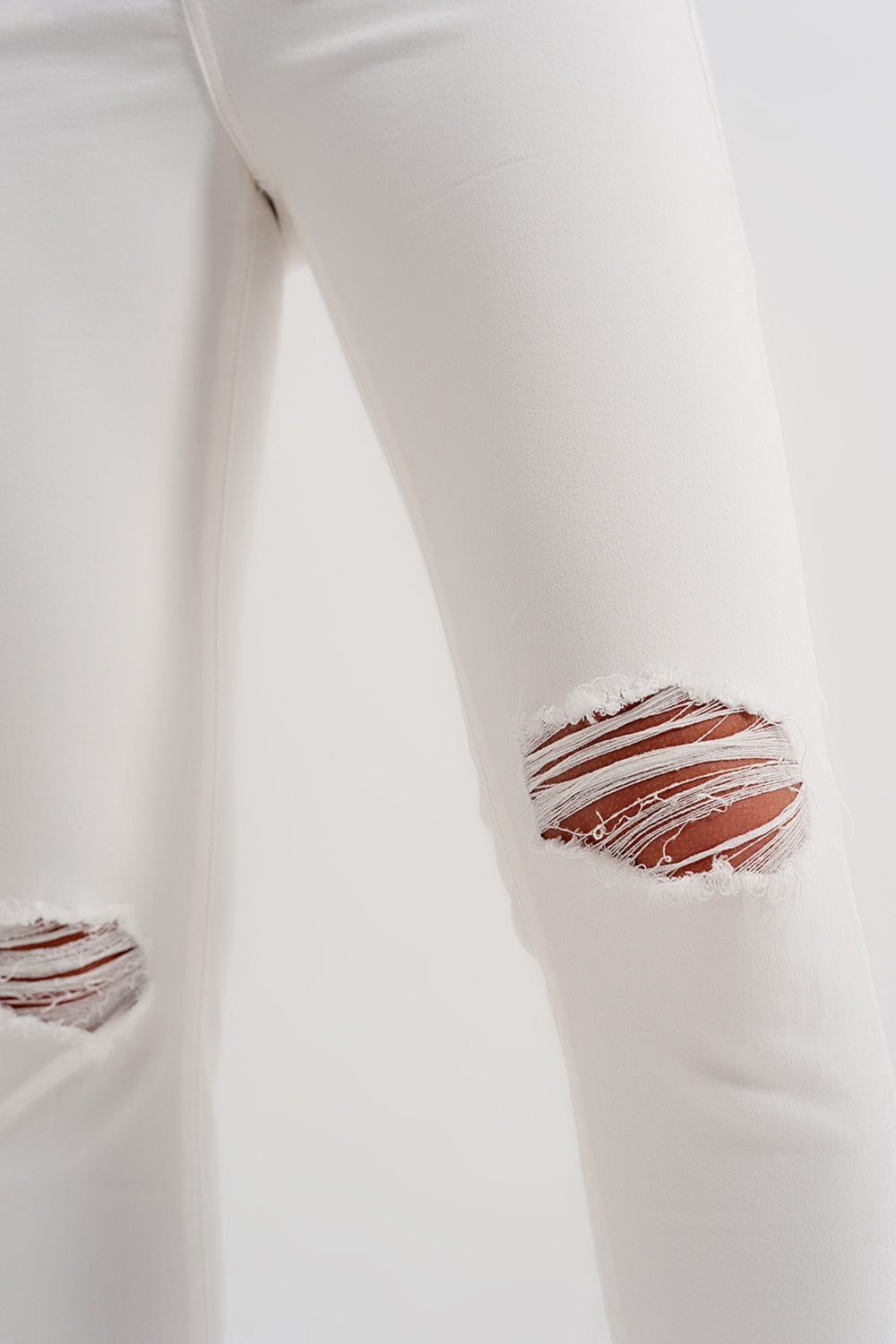 Jeans crema con strappi e fondo sfrangiato