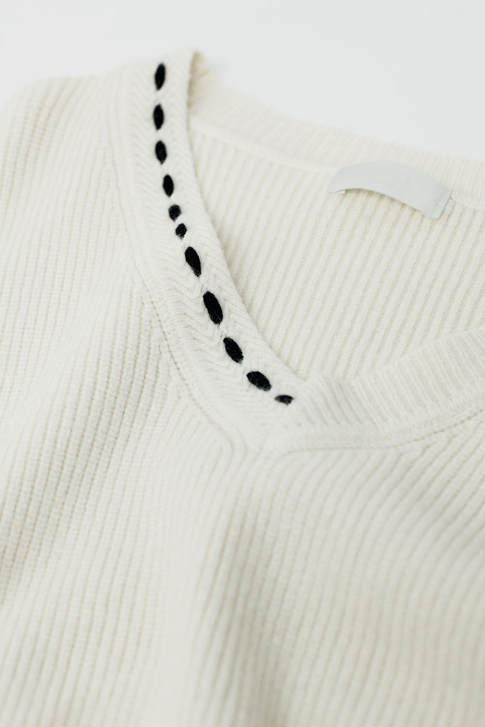 Maglione con scollo a V e dettagli ricamati in nero