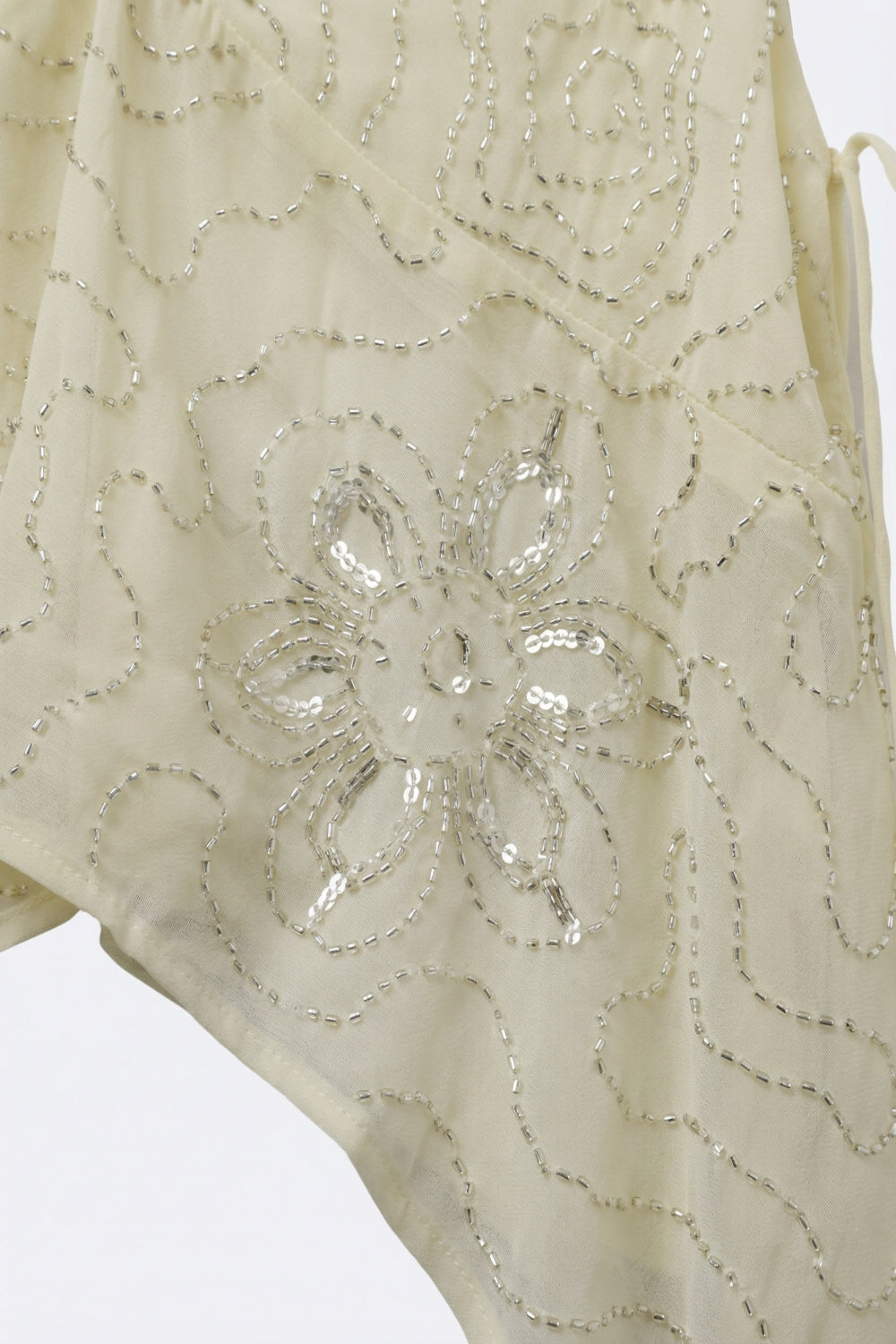 Top crema in chiffon con orlo asimmetrico e decorazione con perline