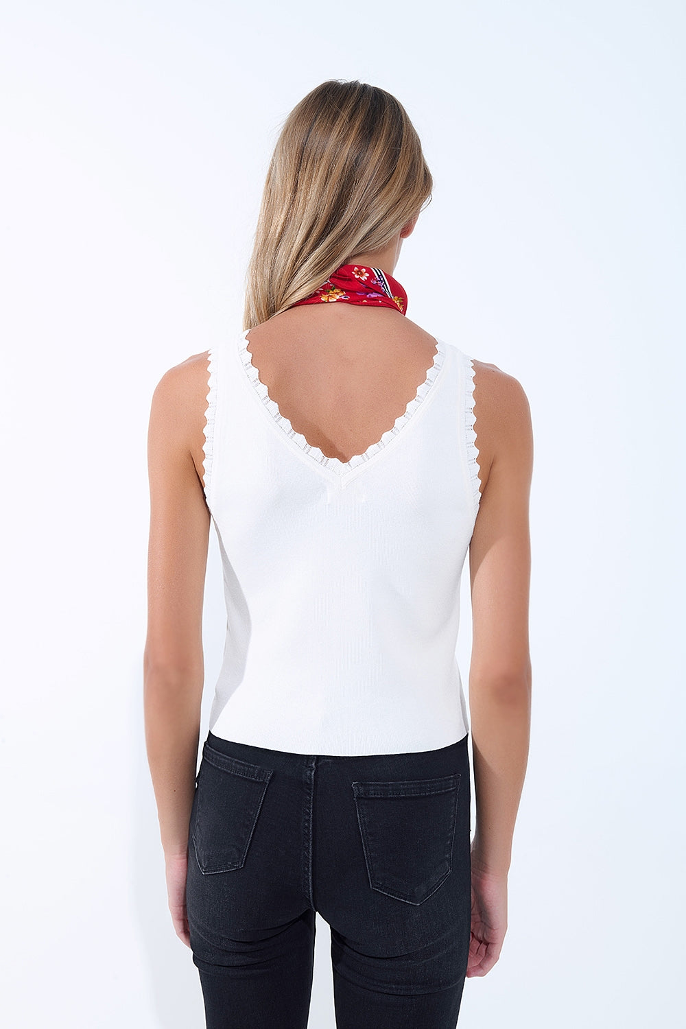 Top in maglia bianca con scollo a V e bordi smerlati