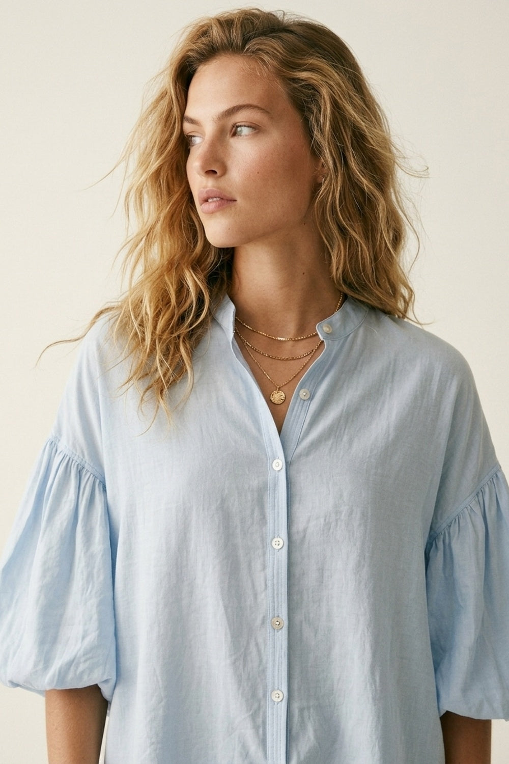Blusa azzurra con maniche a sbuffo e bottoni sul retro