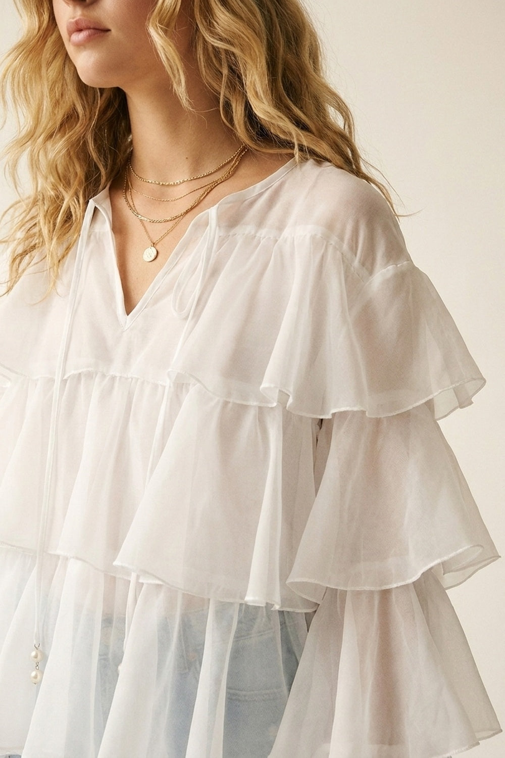 Blusa bianca con volant a strati e peplo con fiocco al collo