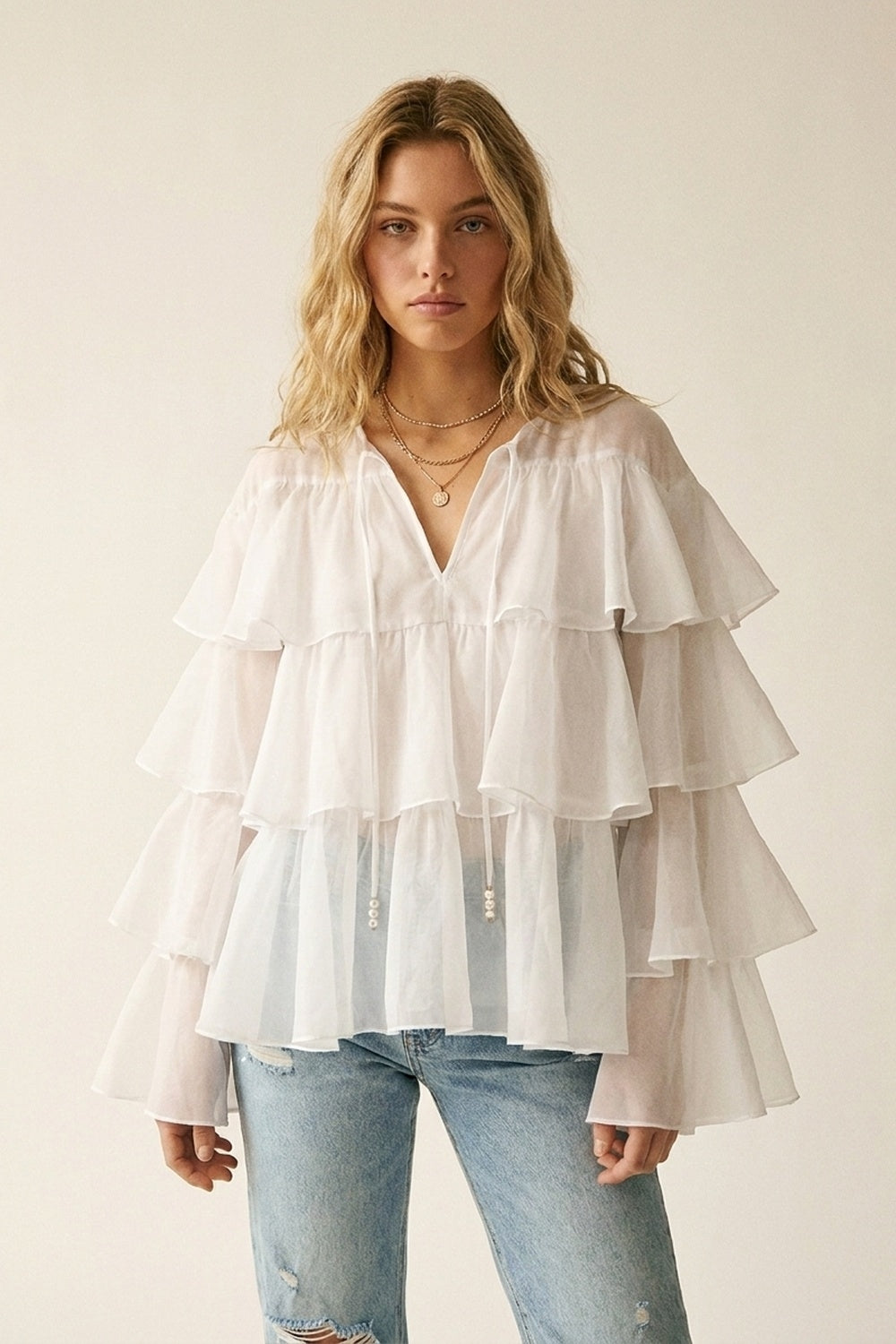 Blusa bianca con volant a strati e peplo con fiocco al collo