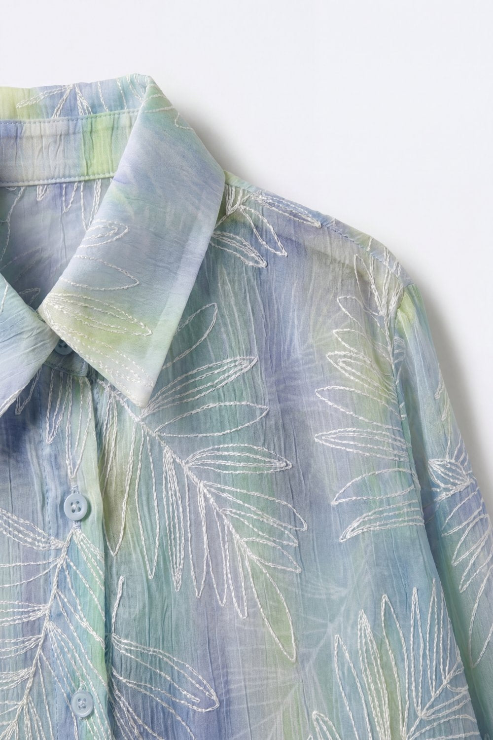 Camicia azzurra con stampa fogliare trasparente e tessuto traslucido