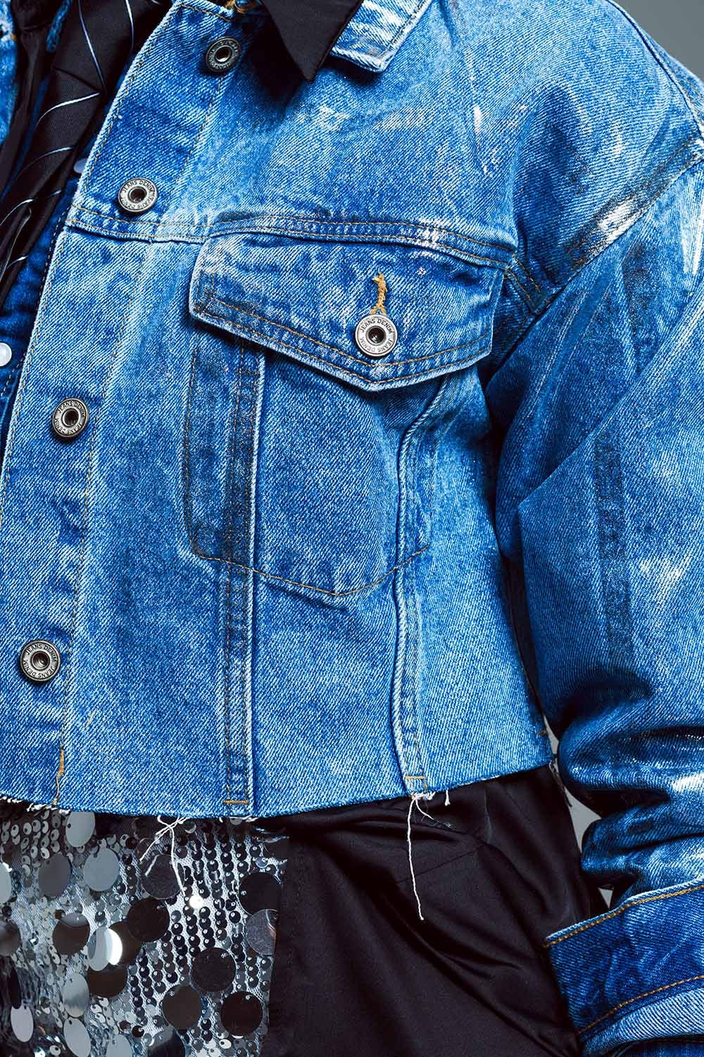 Giacca in denim cropped con orlo a vivo lavaggio medio e finitura argento metallizzato.