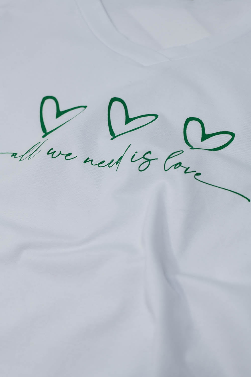 Maglietta bianca con All We Need Is Love in verde