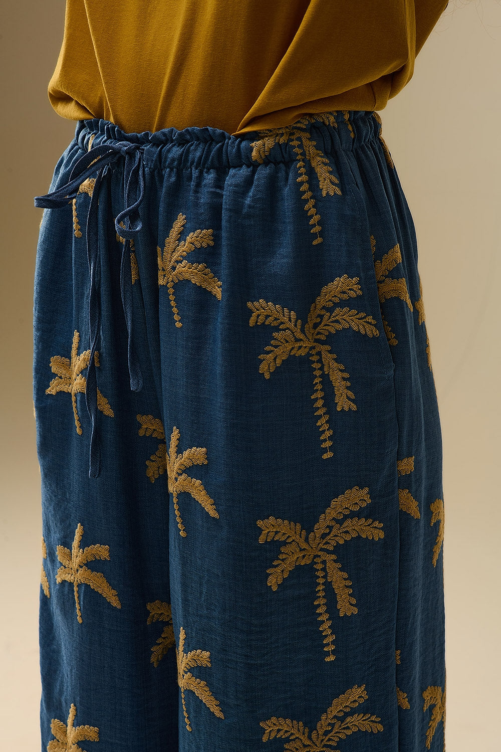 Pantaloni a gamba larga blu con ricamo di palme beige